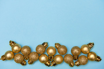 Creative Christmas pattern with golden shiny baubles on blue pastel background, copy space. Minimal, winter, new year concept. Top view, flat lay