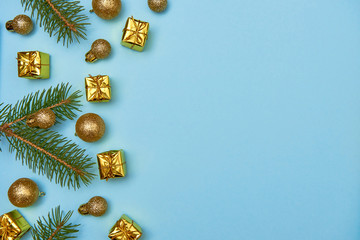 Fototapeta na wymiar Creative Christmas pattern with golden shiny baubles, fir tree branches and gifts on pastel blue background, copy space. Minimal, winter, new year concept. Top view, flat lay