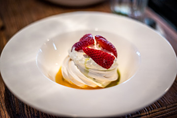 Pavlova with vanilla cream and fresh strawberry and passion fruit coulis