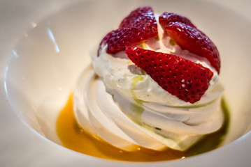 Pavlova with vanilla cream and fresh strawberry and passion fruit coulis