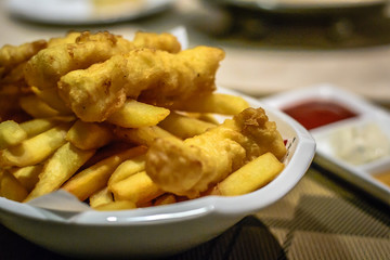 fried fish and chips with tomato ketchup, tartar sauce and mustard sauce on the side