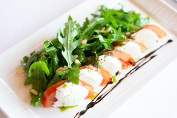 classic italian appetiser of burrata cheese with tomato, and arugula rocket