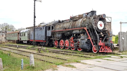 Fototapeta na wymiar An old antique steam locomotive at the site of the Cineville Film Studio in Latvia. May 2019