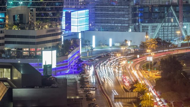Skyline view of intersection traffic on Al Saada street near DIFC night timelapse in Dubai, UAE. Illuminated skyscrapers in financial centre aerial view from above in downtown