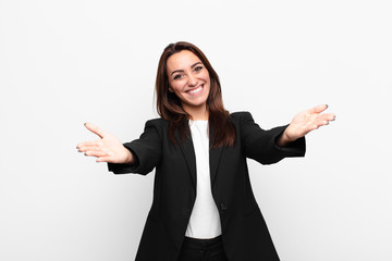 young pretty businesswoman smiling cheerfully giving a warm, friendly, loving welcome hug, feeling happy and adorable against white wall