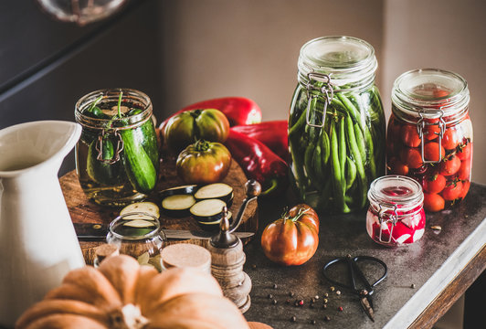 Autumn vegetable pickling and canning. Ingredients for cooking and glass jars with homemade vegetables preserves on concrete kitchen counter. Healthy organic fermented food concept
