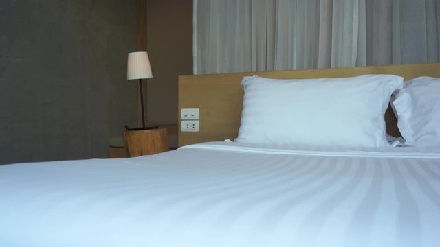 A light breeze rustles the window shears behind a made-up resort bed.
