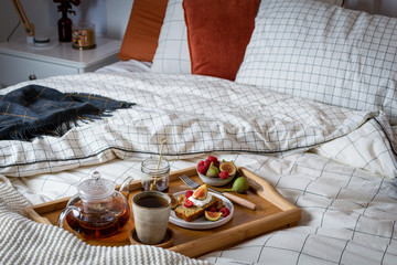 Obraz na płótnie Canvas Breakfast in bed with pastry and fresh fruits, black tea