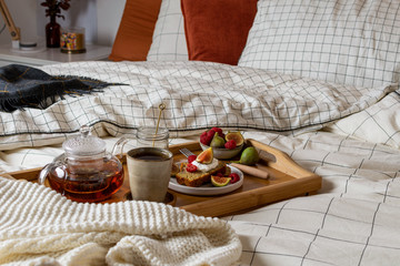Fototapeta na wymiar Breakfast in bed with pastry and fresh fruits, black tea
