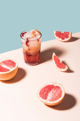 Fresh summer cocktail with pink grapefruit slices. Divided blue and beige bankground. Abstract conception.