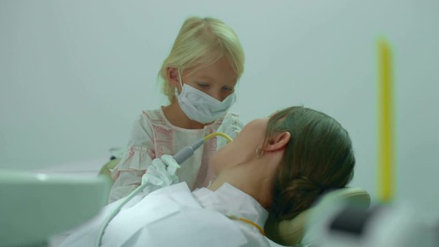 Girl puts saliva ejector into the doctors mouth