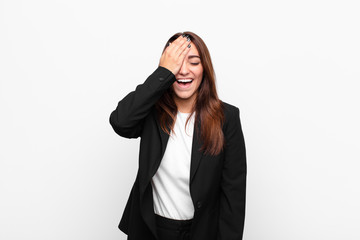 young pretty businesswoman laughing and slapping forehead like saying d‚Äôoh! I forgot or that...