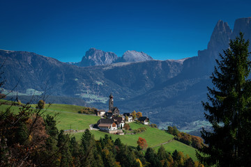 Panoramic view of the village and Nikolaus church of Mittelberg with the Langkofel, Plattkofel and Rosengarten mountains in the background