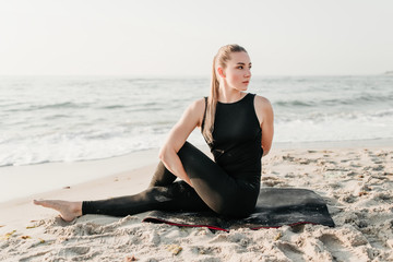 Fototapeta na wymiar beautiful sporty woman doing yoga on the beach near ocean