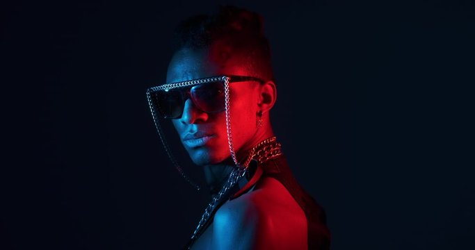 Rear view of African man turning around wearing chain necklace and fancy goggles in ultraviolet light