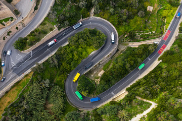 Colorful trucks on the curves road in Mellieha city. Top aerial view. Malta country