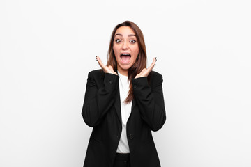 young pretty businesswoman feeling shocked and excited, laughing, amazed and happy because of an...