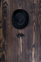 Men's hat and mustache in the form of lollipop  on wooden background.