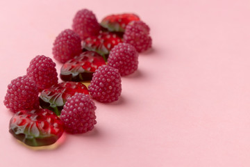 Jelly candies on a pink background. Sweets in the form of strawberries and raspberries in a row. Copy space.