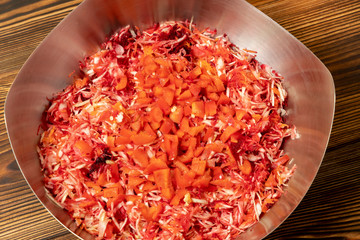Vegetable veggie salad in a metal bowl on a wooden background.