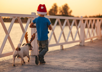 Holidays at beach concept with child and dog wearing Christmas and New Year costumes at seafront