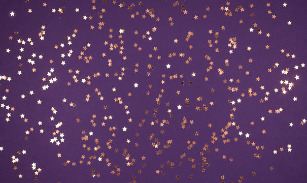 little gold stars on purple background Festive holiday background. Celebration concept. Top view,