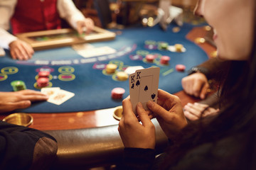 Close-up hands of a poker player checking cards in a casino.