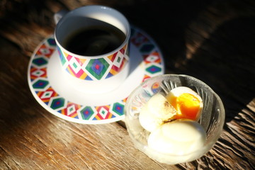 Black coffee with boiled eggs on a wooden table