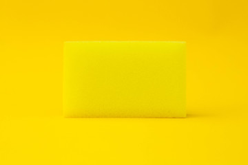 Yellow cleaning sponge on a yellow background. The view from the top. Space for text