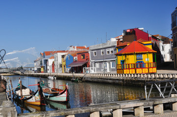 Fototapeta na wymiar Traditional colored boats on the water, water canal and city. Colored houses by the river on the shore . Aveiro. Portugal. Europe.