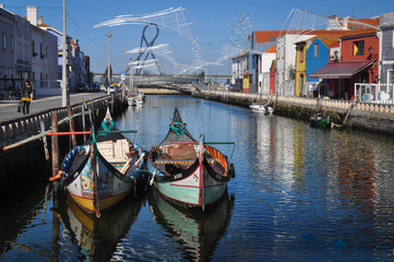 Fototapeta na wymiar Traditional colored boats on the water, water canal and city. Colored houses by the river , moliceiros. Aveiro. Portugal. Europe.