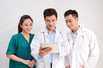 Fototapeta premium Medical team includes doctors and nurse looking at an ipad/tablet computer together