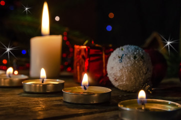 Many candles on a wooden background, branches of a Christmas tree, a red cap. Beautiful, magical Christmas and new year background