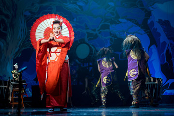 Traditional Japanese performance. Actress in traditional red kimono dances with umbrella