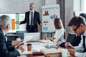 Modern businessman conducting a presentation while having staff meeting in the board room