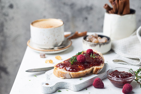 Toasted bread with sweet raspberry jam for breakfast on light background