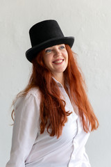 Beautiful red-haired woman wearing white shirt and black hat