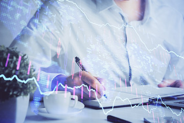 Fototapeta premium Double exposure of man's hands writing notes of stock market with forex chart.