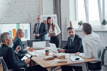 Successful business professionals presenting analytical report while working together with...