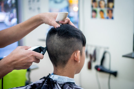 An Asian Boy In The Barbershop  ,Boy Getting Haircut By Barber In Barbershop