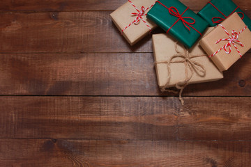 Pile of Christmas gifts on brown wooden table. Christmas rustic background. New Year, winter holiday, copy space, top view, present boxes