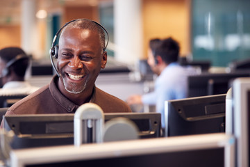 Mature Businessman Wearing Telephone Headset Talking To Caller In Customer Services Department - Powered by Adobe