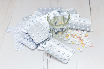 Colorful medical pills with a glass of water on the table, for your text