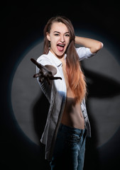 Beautiful slim topless girl wearing jeans and an unbuttoned shirt poses in a spotlight circle. Creative, conceptual, design.