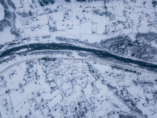Calm and cosy fairy-tale village Kryvorivnia covered with snow in the Carpathians mountains, aerial view. Typical landscape in Hutsulshchyna National Park in Ukraine. Vacation and winter sports.