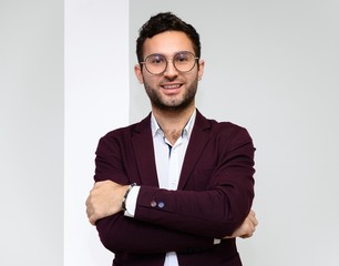 The concept is all ok, everything is going well. Photo of a handsome young man in glasses, in a jacket showing a smile and satisfaction on a creative background.