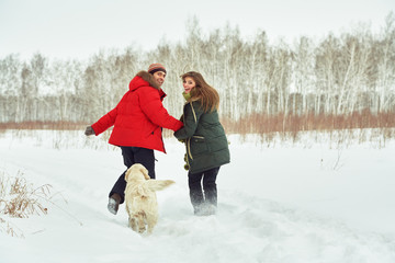 Fototapeta na wymiar couple with a dog on a winter walk. man and woman with labrador outdoors
