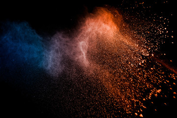 Fototapeta na wymiar Orange blue powder explosion on black background.Orange blue color dust splash clouds.