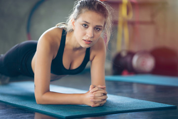 Young woman doing plank at gym or fitness, workout in middle of body to build muscle at belly stronger with serious face and concentrate her exercise. Under instructor control fat, diet and weight
