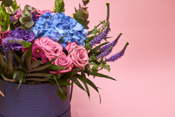 Beautiful bouquet of pink, purple and blue flowers in big violet hat box on pastel pink background, copy space. Greeting card for Womens Day, Mothers Day, Valentines Day, wedding, birthday